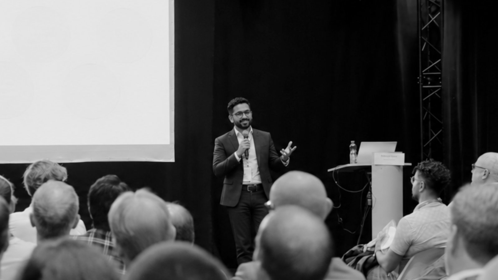 Hettore Blatti, COO of Hans Blatti, speaking on stage with a microphone in front of a full audience at a startup expo